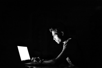 man typing on computer in the dark